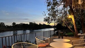 An outdoor terrace with round tables and chairs, overlooking a river. - Morocco blue cafe by chilong river farm  (Kosum Phisai)