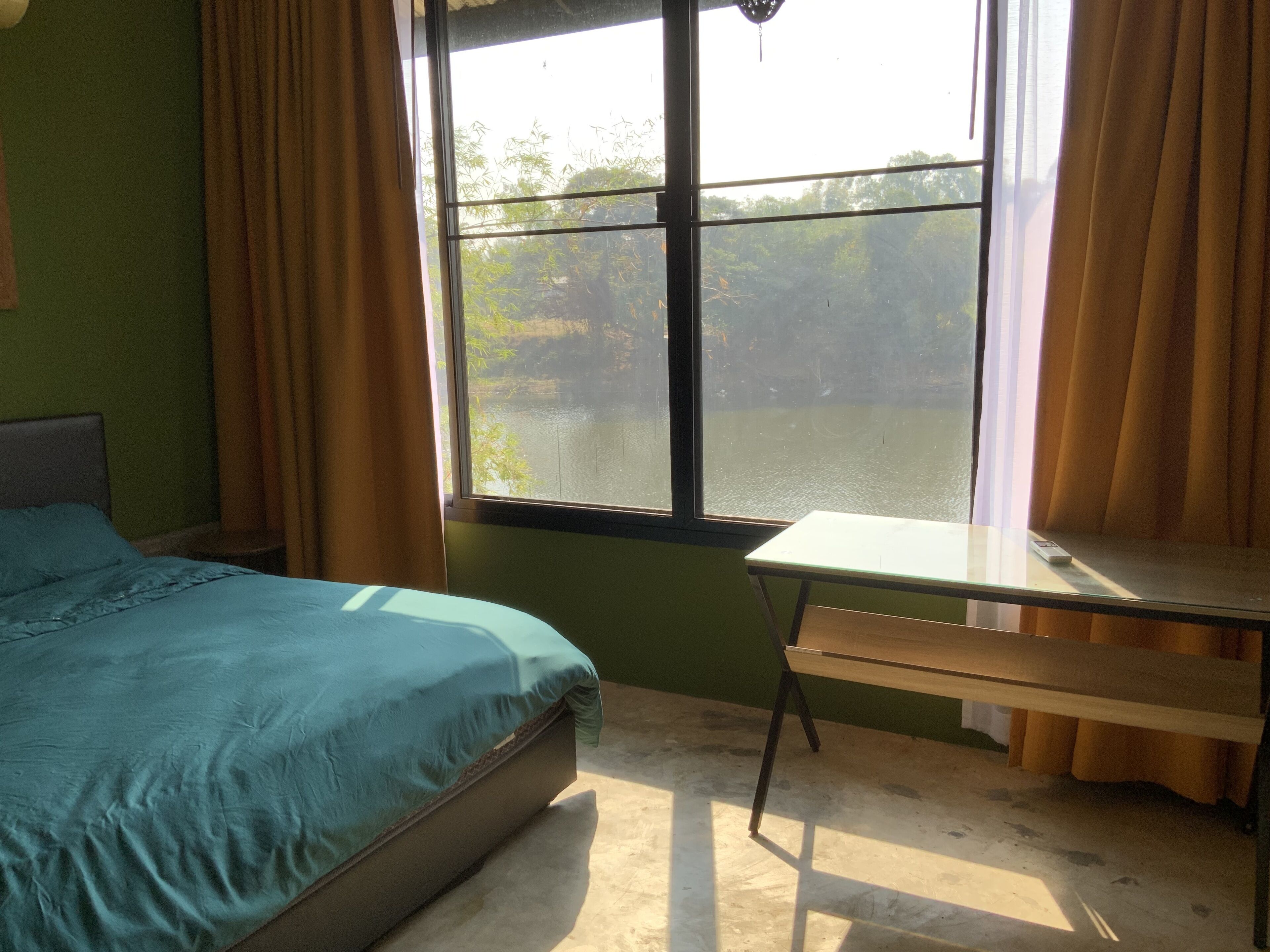 A bedroom with a bed, a desk, and a window with curtains.