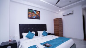 A modern hotel room with a large bed, a painting on the wall, an air conditioning unit, and a wooden wardrobe. - Hotel Lyf Corporate Suites Noida Sec-56 (Noida)
