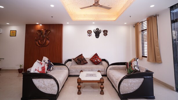 A living room with a ceiling fan, two sofas, a coffee table, and decorative wall art. - Hotel Lyf Corporate Suites Noida Sec-56 (Noida)