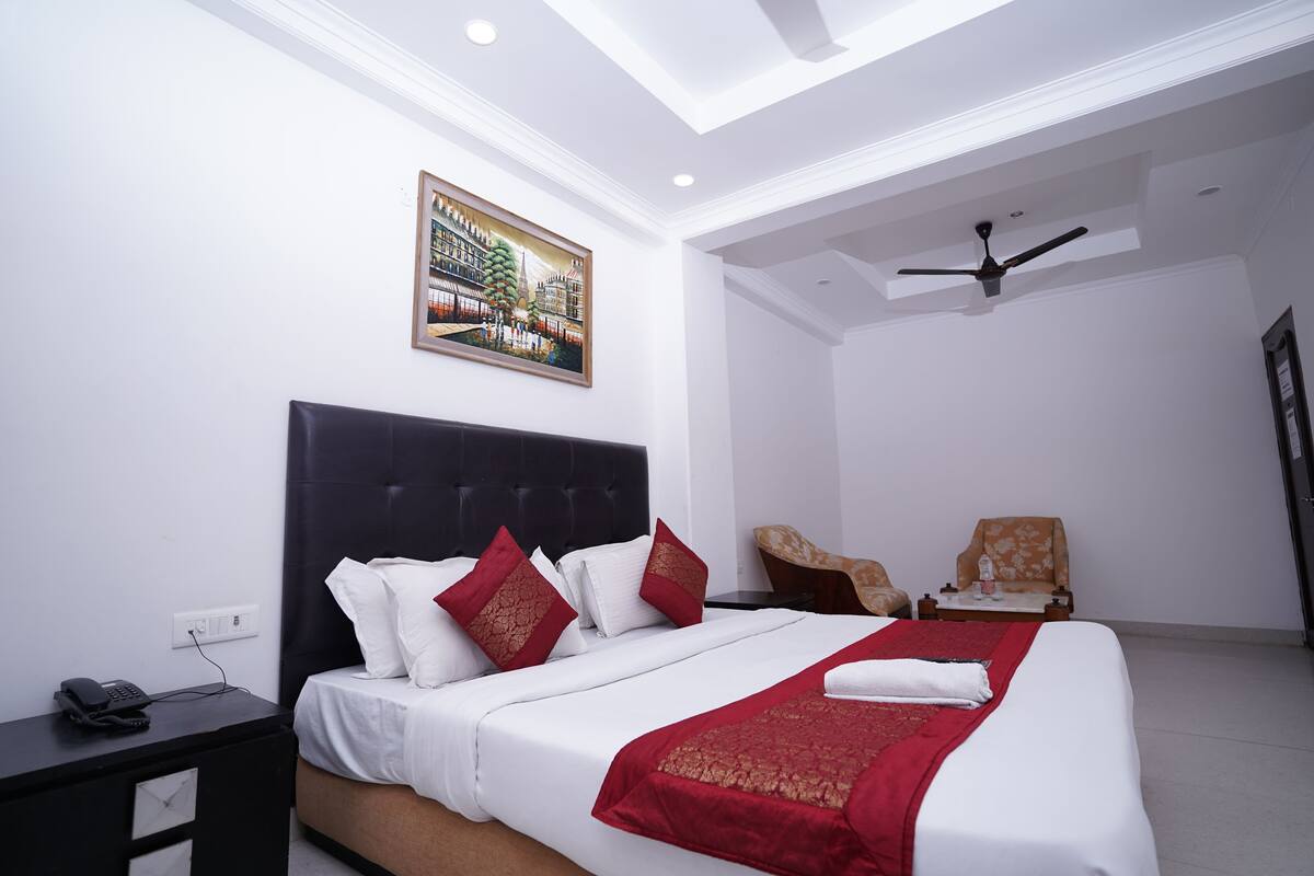 Una habitación de hotel moderna con una cama grande, un ventilador de techo y un cuadro en la pared.