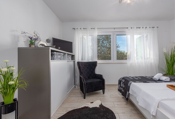 Une chambre à coucher avec un lit, une chaise, un bureau et une fenêtre avec des rideaux.