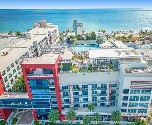 A hotel complex with multiple buildings, a swimming pool, and a view of the ocean.