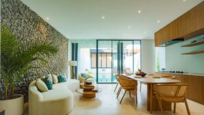 Un salon moderne avec un mur en pierre, un canapé avec des coussins, une table basse et un coin repas comprenant une table et des chaises.