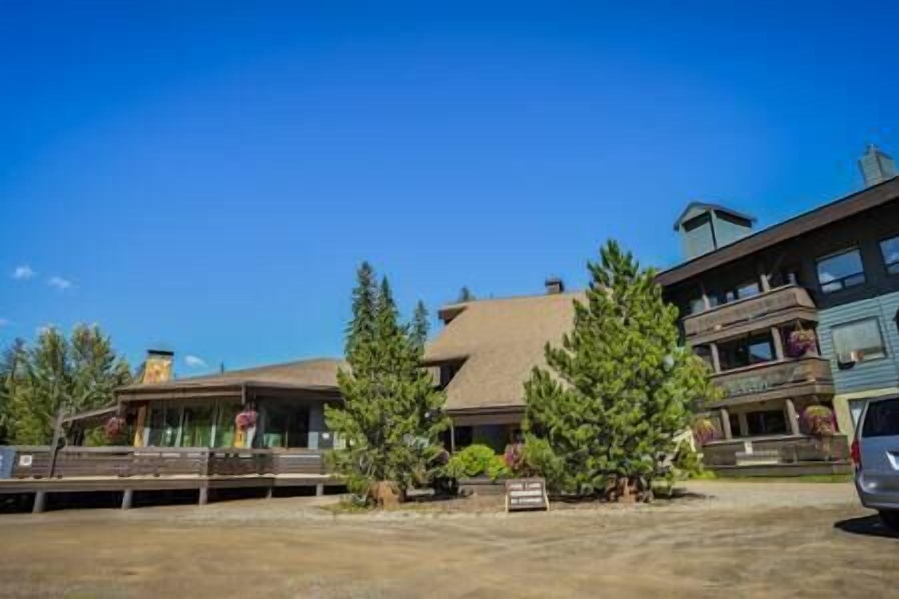 A building with a sloped roof, large windows, and a balcony. There are trees in front of the building.