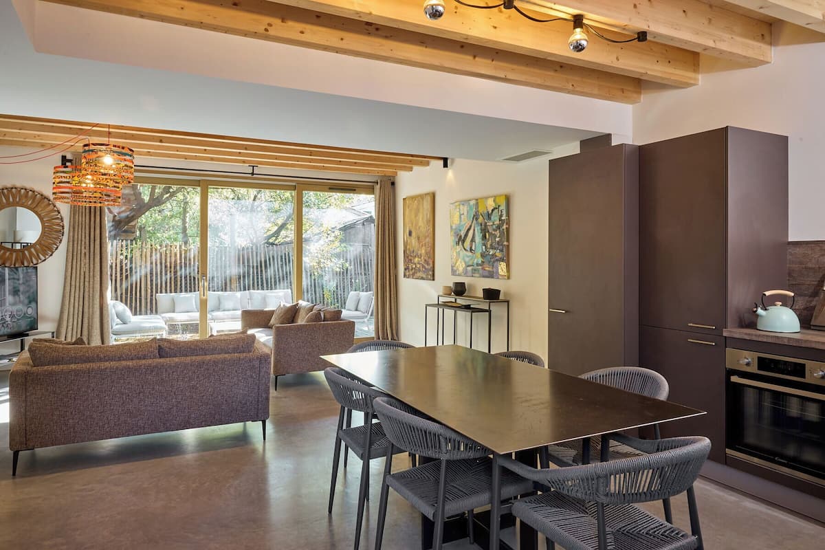 A modern kitchen with dark cabinets, a built-in oven, and a kettle on the countertop.