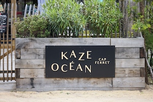 Un letrero que dice 'Kaze Ocean Cap Ferret', con una estructura de madera y plantas al fondo.