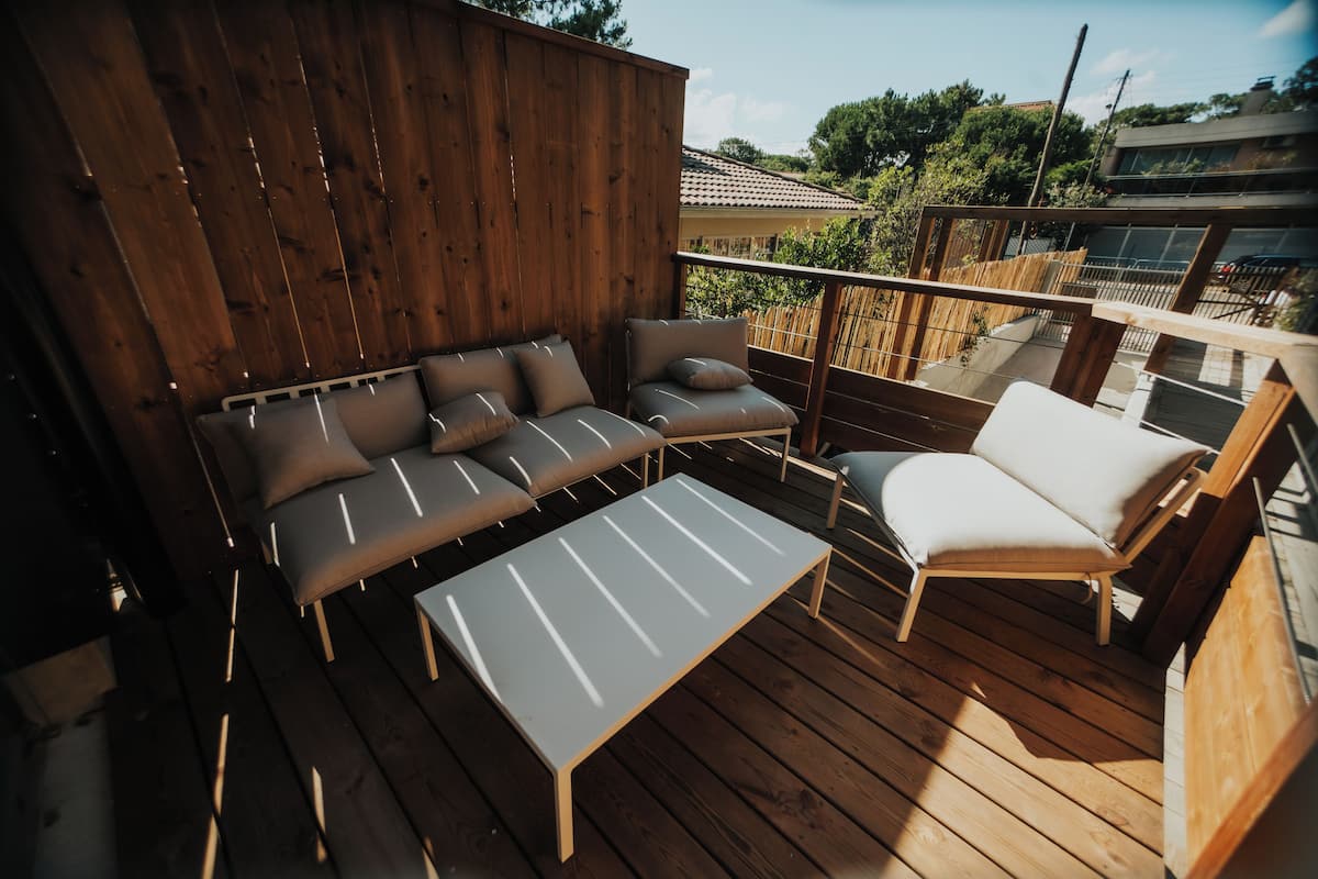 A wooden deck with a sofa set, a single chair, and a small table.