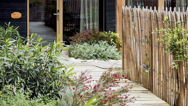 A wooden deck leading to a modern building with large windows and a wooden fence. - Kaze Océan The Originals Relais (Lège-Cap-Ferret)