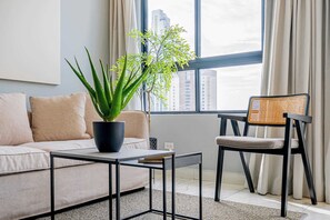Una sala de estar moderna con un sofá, una mesa de centro, una silla y una planta en maceta.