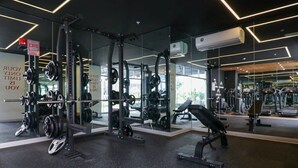 Un gimnasio moderno con equipo de levantamiento de pesas, paredes espejadas y frases motivacionales.