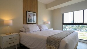 Una habitación de hotel moderna con una cama grande, dos mesitas de noche, un revestimiento de pared de madera y vistas a la ciudad a través de la ventana.