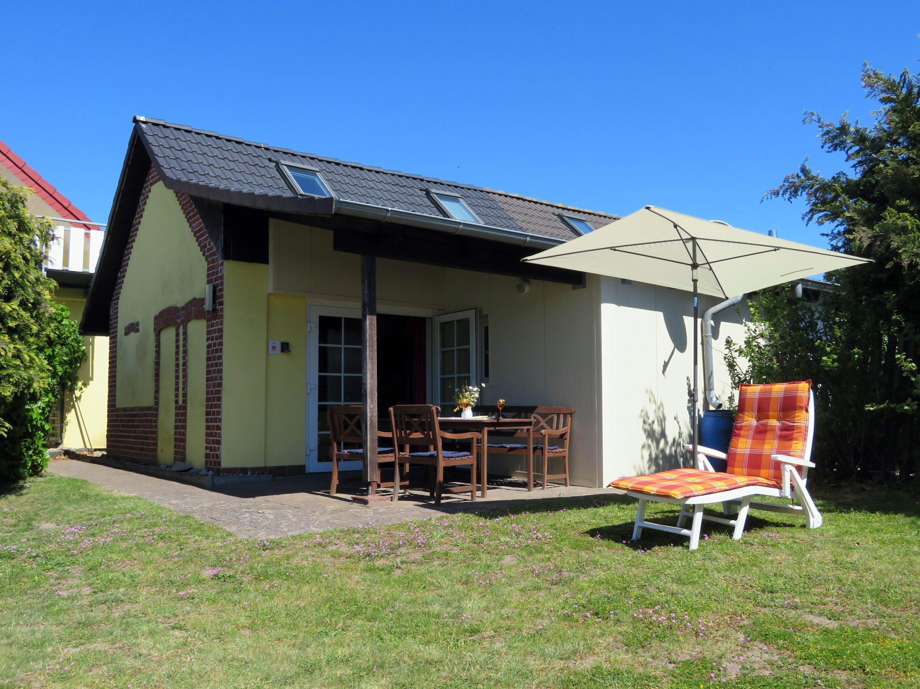 A small house with a patio, a table, and two chairs.