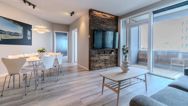 A modern living room with a dining area, a stone fireplace, and a large TV.