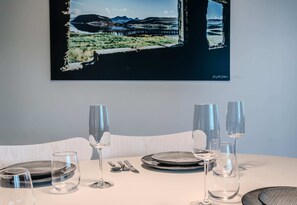 Enjoy meals in this elegant dining area with a beautifully set table and a stunning artwork above.