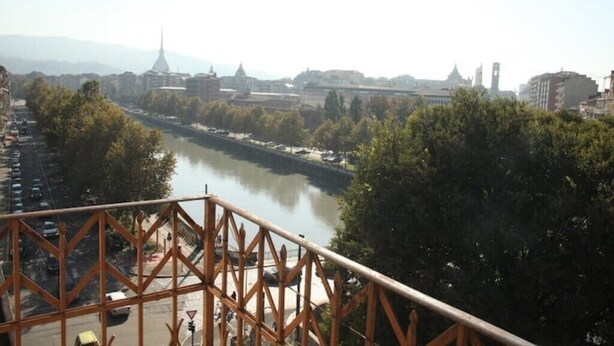 A river with buildings and trees in the background. - Panoramic two-room apartment on the banks of the Dora River - Da Momo (Torino)