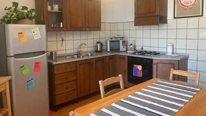 A kitchen with wooden cabinets, a refrigerator, a microwave, a stove, and a dishwasher. - Panoramic two-room apartment on the banks of the Dora River - Da Momo (Torino)