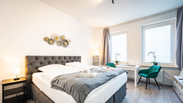 Una camera da letto moderna con un letto grande, comodini, una scrivania e una sedia.
