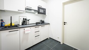 Una cucina moderna con mobili bianchi, un piano di lavoro nero, un forno a microonde e una macchina per il caffè.