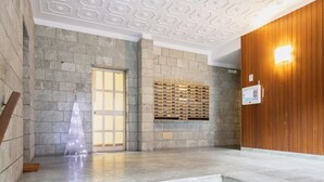 A lobby with stone walls, a wooden panel wall, a glass door, and a built-in wooden shelf. - Easylife - Charming nest in Sant'Ambrogio (Milano)