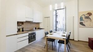 Une cuisine moderne avec des meubles blancs, un plan de travail en bois et un coin repas comprenant une table et des chaises.