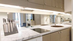 A modern kitchen with a marble countertop, stainless steel appliances, and a built-in sink.