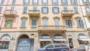 A multi-story building with a row of shops on the ground floor, including a pharmacy.