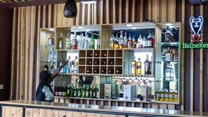 A bar with wooden paneling and shelves stocked with various liquor bottles. - The Country Inn by Smart Haven (Kigali)