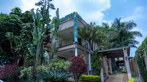 A hotel with a modern design, surrounded by lush greenery and palm trees. - The Country Inn by Smart Haven (Kigali)