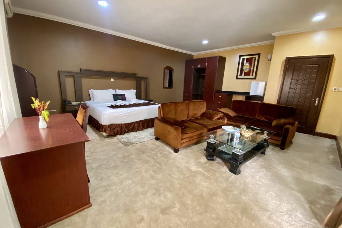 Una habitación de hotel con una cama, dos sofás, una mesa de centro y un escritorio.