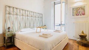 A bedroom with a large bed, a bedside table, a radiator, and a window.