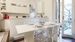 A modern kitchen with white cabinetry, a central island with seating, and a view through a glass door to an outdoor area.
