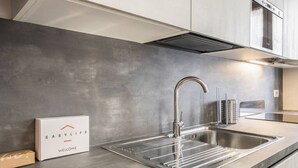 A modern kitchen with a stainless steel sink, a built-in range hood, and a minimalist design.