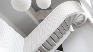 Una escalera de caracol con acabado blanco que lleva a un piso superior.