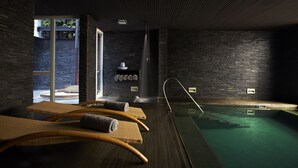 Un área de piscina interior moderna con sillones reclinables y vistas despejadas al exterior.