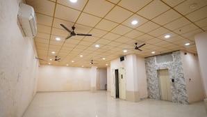 A spacious, well-lit room with a tiled floor, ceiling fans, and an elevator. - Hotel Lyf Corporate Suites - Peera Garhi (New Delhi)