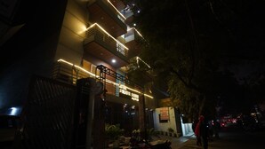 A multi-story hotel with illuminated balconies and a sign indicating it is a hotel and a metro station. - Hotel Lyf Corporate Suites - Peera Garhi (New Delhi)