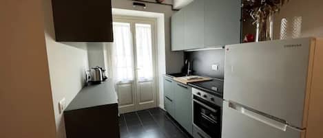 Una cocina compacta con refrigerador, estufa y armarios.
