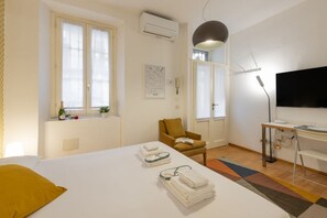 Ein Hotelzimmer mit Bett, Schreibtisch, Stuhl, Fernseher und Fenster.