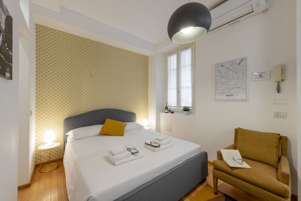 Habitación de hotel con cama, una silla, un mapa en la pared y una ventana.