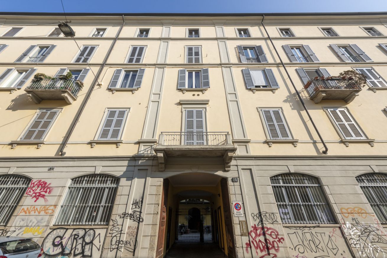Un immeuble à plusieurs étages doté de balcons, d’une entrée principale et dont les murs sont recouverts de graffitis.