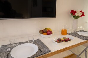 Un desayuno servido con un bol de fruta, jugo y un plato de postre sobre una mesa con una servilleta de diseño.