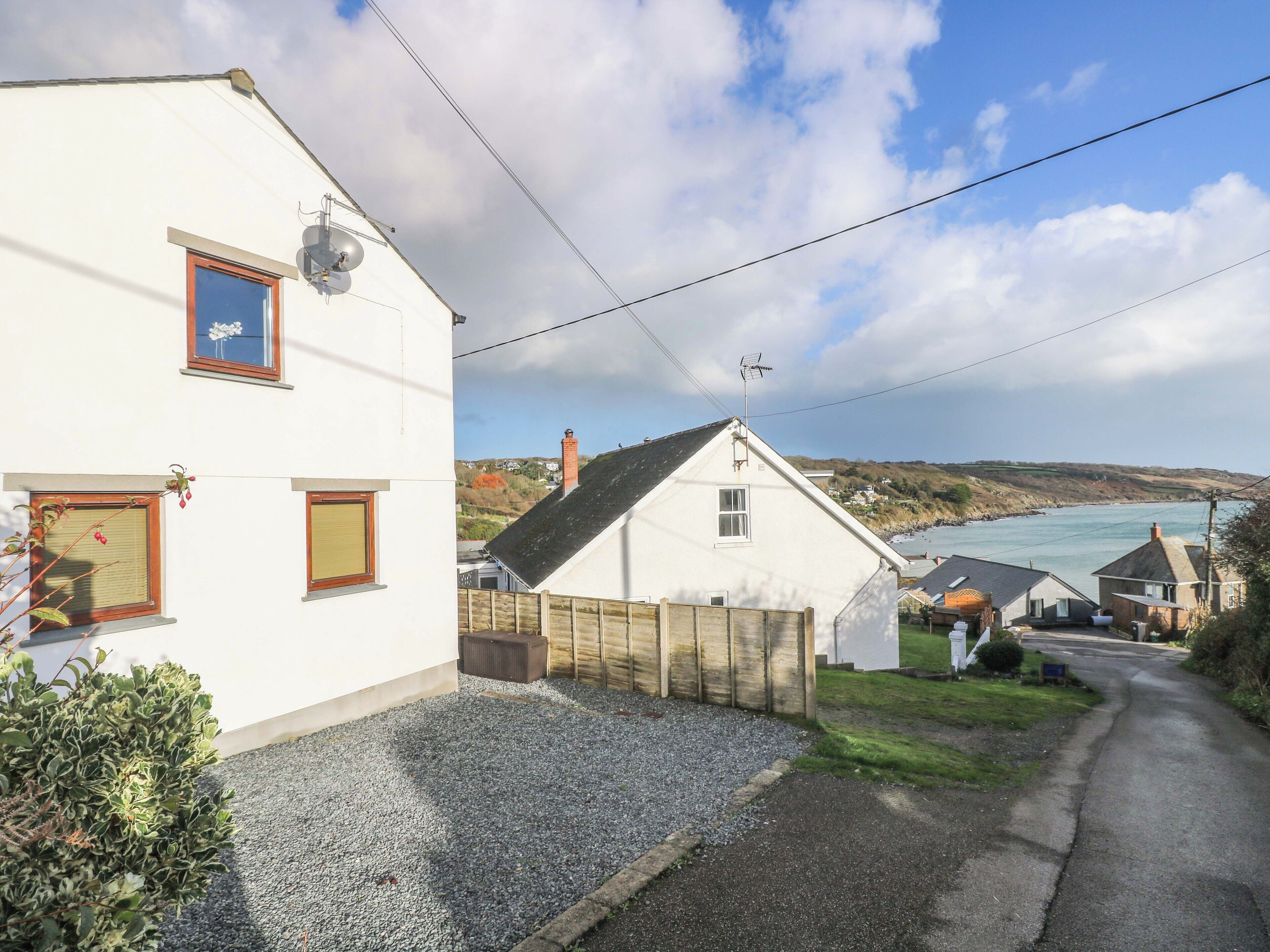 A coastal village with white houses, a gravel driveway, and a view of the sea.