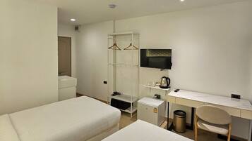 A hotel room with two beds, a desk, a TV, a wardrobe, and a trash bin.
