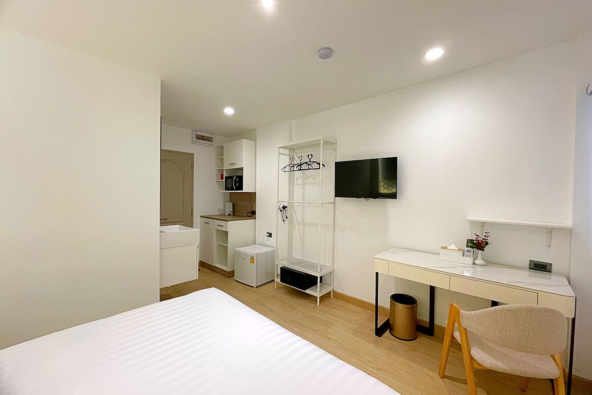 Une chambre d’hôtel moderne équipée d’un lit, d’un bureau, d’une télévision et d’un espace douche.