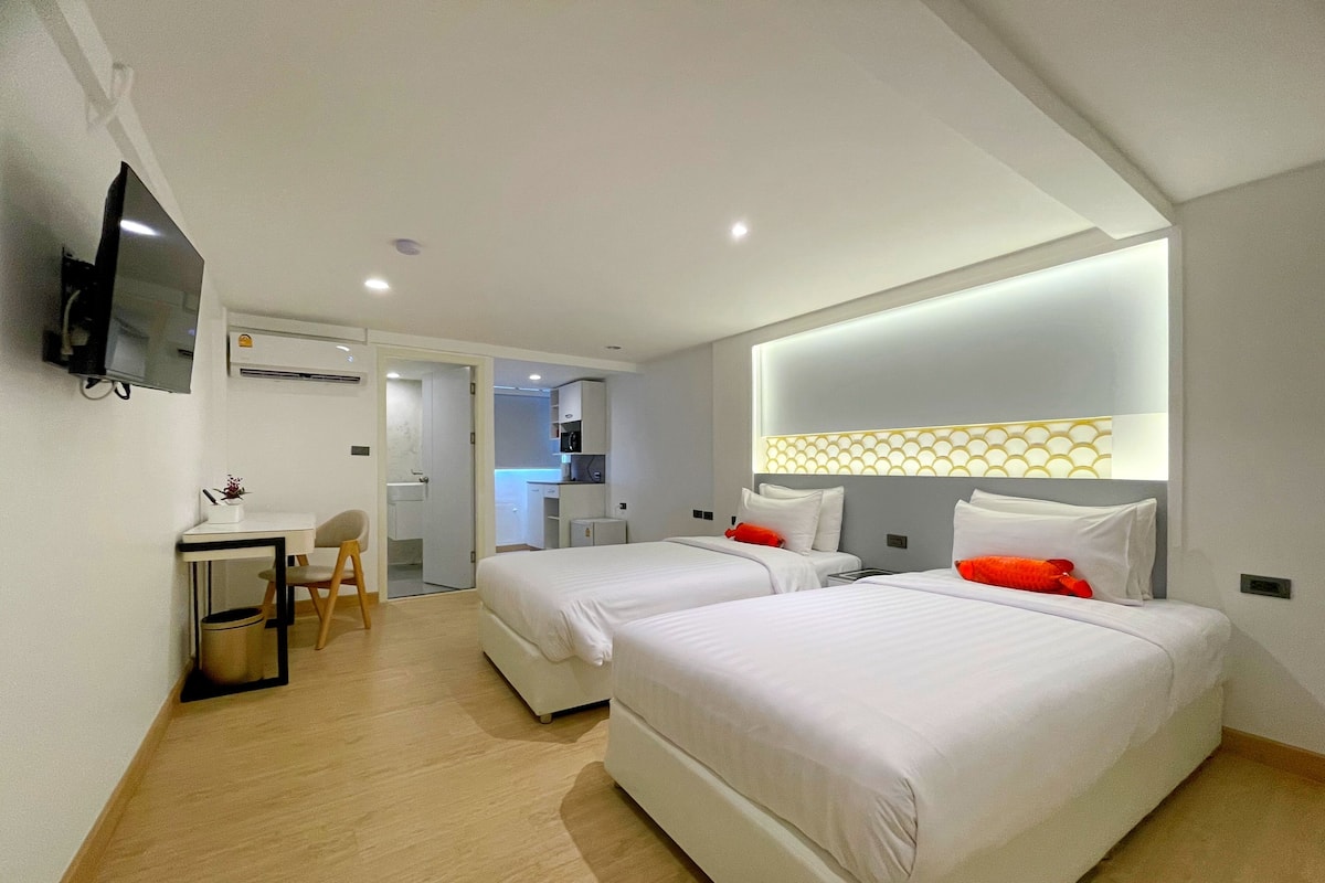 Une chambre d’hôtel avec deux lits, un bureau et une télévision.