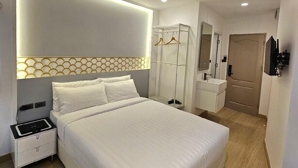 Ein modernes Hotelzimmer mit einem großen Bett, einem Nachttisch und einem Schrank mit Spiegel.