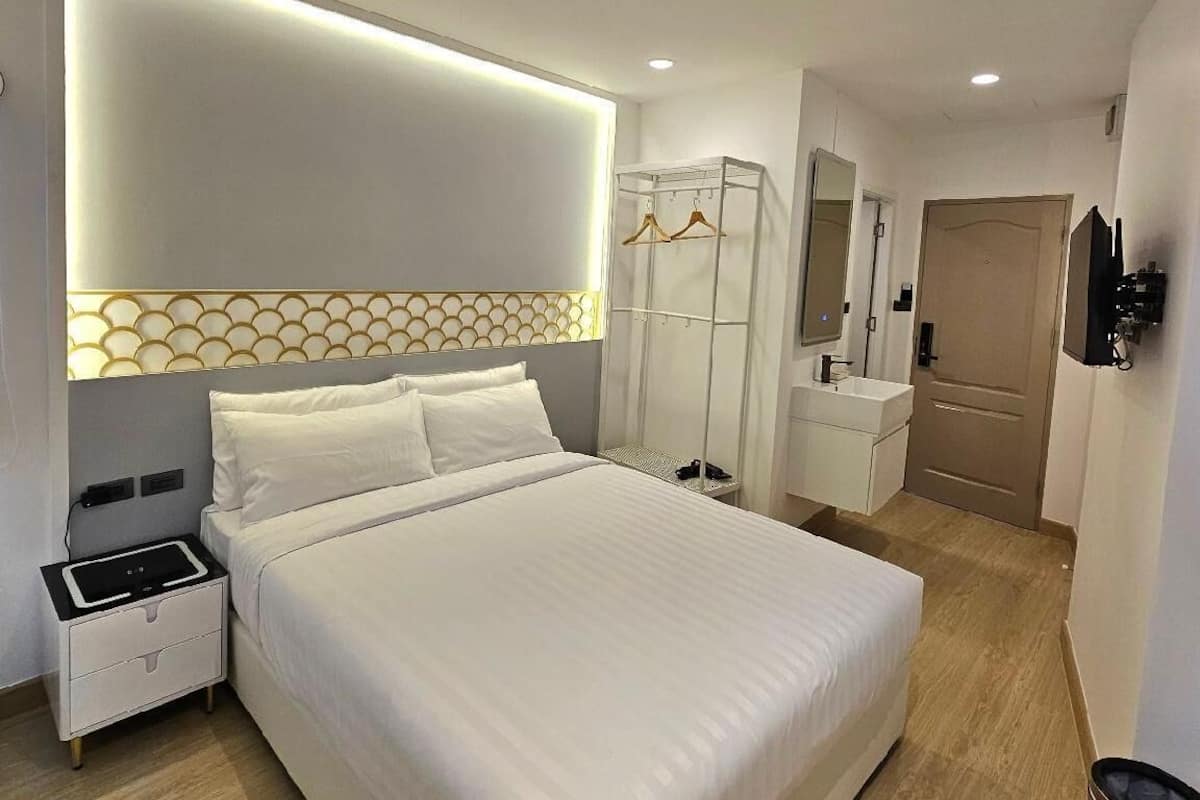 Une chambre d’hôtel moderne avec un grand lit, une table de chevet et une armoire avec un miroir.