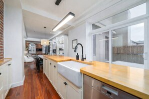 Une cuisine moderne avec un plan de travail en bois, des armoires blanches et une grande fenêtre.
