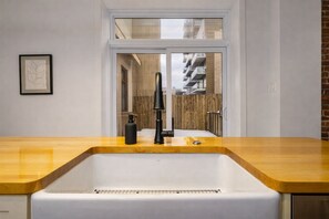 Eine moderne Küche mit einem großen Spülbecken, einer Holzarbeitsplatte und Blick auf einen Balkon mit Holzzaun.